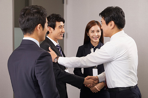 Businessmen and a woman handshake and smile