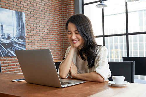 A lady happily using a laptop