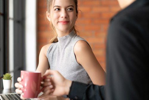 A young woman using laptop and talking to another man